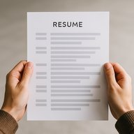 Две руки держат аккуратно оформленное резюме с чёткой ритмичной структурой блоков